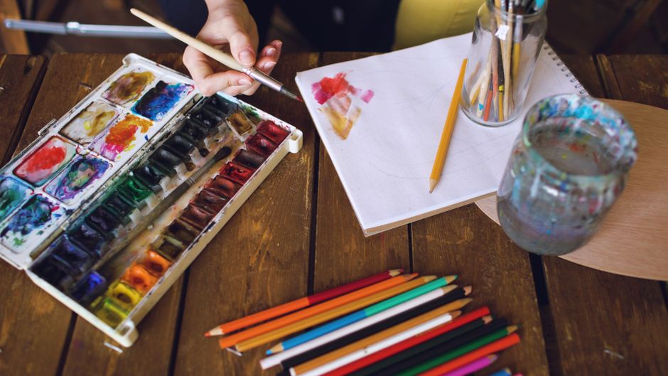 A vibrant artist workspace featuring watercolors, pencils, and a sketchbook, ready for creative expression.
