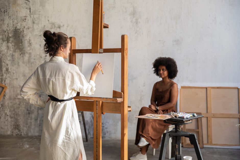 Artist at an easel painting a model in an art studio. Creativity in motion.
