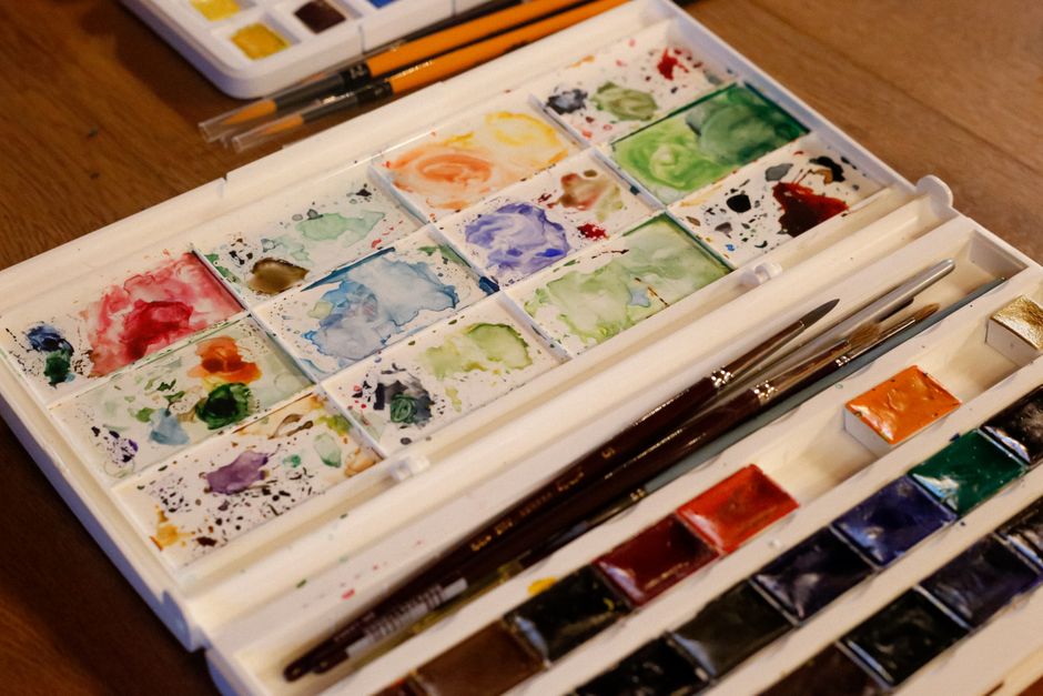 A vibrant watercolor paint set and brushes on a wooden table, perfect for artists.